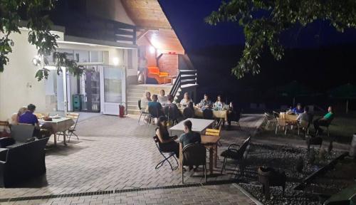 a group of people sitting at tables in a patio at night at KONAK LJUBICA Rtanj in Boljevac