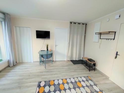 a living room with a table and a television on a wall at Lovely flat nearby Paris fully redone with free parking on premises and balcony in Clichy