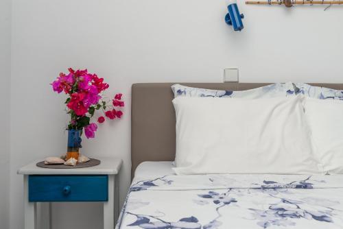 a bed with a vase of flowers on a night stand next to a bed at Antoniadi Rooms in Livadia