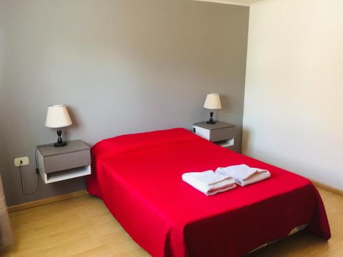 1 cama roja en una habitación con 2 lámparas en Newen en El Calafate