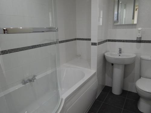 a bathroom with a tub and a toilet and a sink at Waverley Hotel in Workington