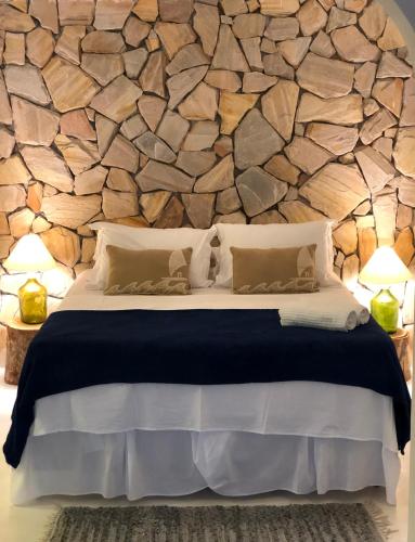 a bedroom with a stone wall with a bed at Kûara Pipa in Pipa