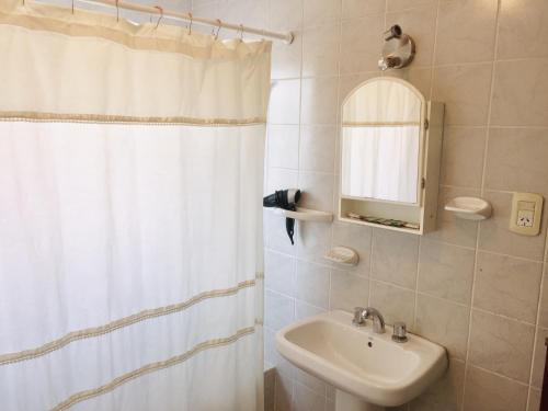 a bathroom with a white shower curtain and a sink at Newen in El Calafate