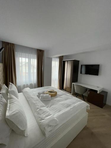 een groot wit bed in een slaapkamer met een bureau bij Adina Apartament in Gura Humorului