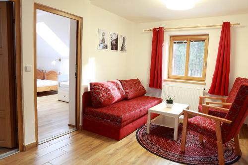a living room with a red couch and a table at Rezidence Kouty in Loučná nad Desnou