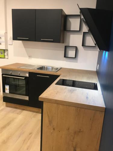 une cuisine avec des armoires noires et un comptoir en bois dans l'établissement LOFT T2 by locations_lepuyenvelay, au Puy-en-Velay
