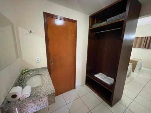a bathroom with a sink and a wooden door at IPÊ PARK Convention Hotel in Sao Jose do Rio Preto