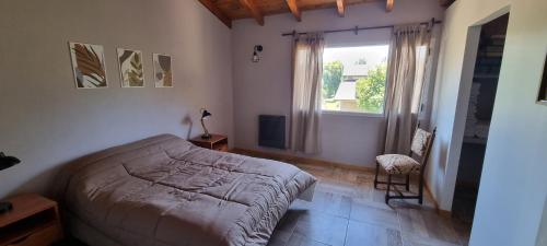 Un dormitorio con una cama y una ventana y una silla. en El Gran Montañes, en Lago Puelo