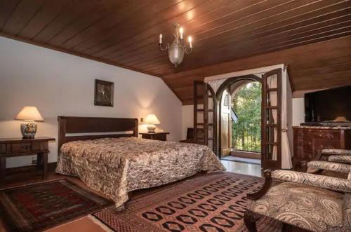 a bedroom with a bed and a large window at Aconchegante Mansão Estilo Suíça em Campos do Jordão in Campos do Jordão