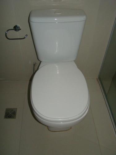 a white toilet in a bathroom with the lid down at Sur Backpackers in Santa Cruz de la Sierra