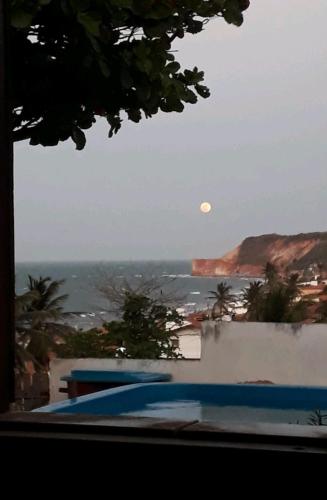 a view of the ocean and the moon from a house at Pousada Chalés do Castelo in Icapuí