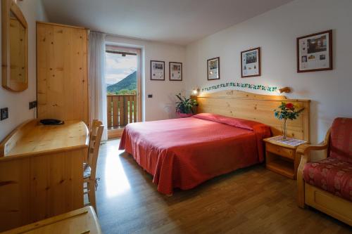 sypialnia z łóżkiem z czerwonym kocem i oknem w obiekcie HOTEL La Locanda w mieście Pinzolo