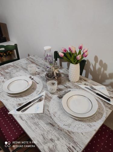 einem Holztisch mit Platten und einer Vase aus Blumen in der Unterkunft Casina Margot in Santa Fiora