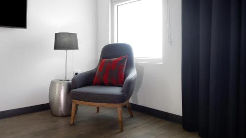 a chair with a red pillow sitting next to a window at Semaphore Splash Apartments in Port Adelaide