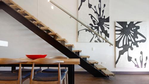 a dining room with a table and a staircase at Semaphore Splash Apartments in Port Adelaide