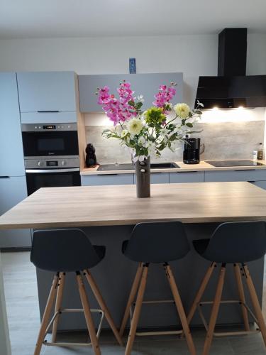 une cuisine avec une table avec un vase de fleurs dans l'établissement Ti Korelo Maison Plélauff 5 chambres, à Prelauff