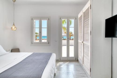 a white bedroom with a bed and a tv at The view 1 in Kampos Paros