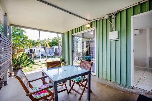 a dining room with a glass table and chairs at Bush Village Holiday Cabins in Airlie Beach