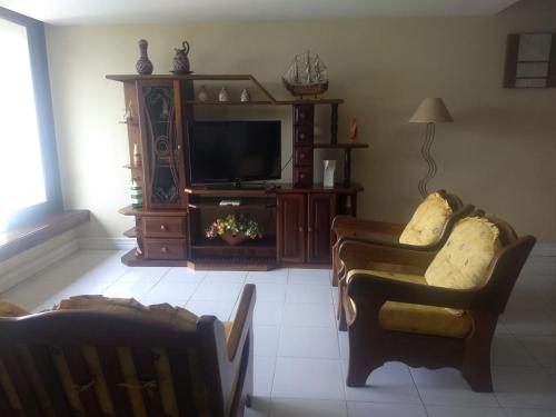 a living room with two chairs and a television at Apartamento Condomínio Porto Bracuhy in Angra dos Reis