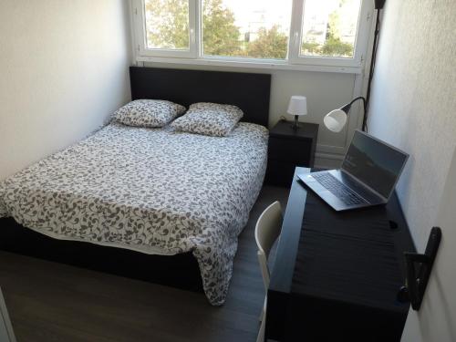 a bedroom with a bed and a laptop on a desk at Résidence Kerhallet in Brest