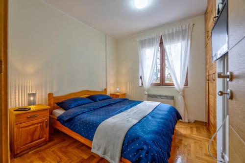 a bedroom with a bed with blue sheets and a window at Apartman Sanjalica in Zlatibor