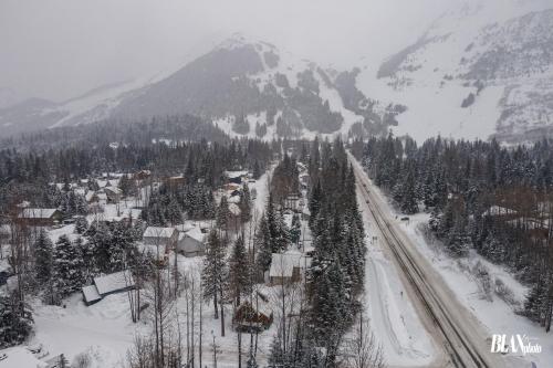 a snow covered village with a road and a mountain at Chair Four Por Favor - Walk Almost Anywhere at Alyeska Resort! in Girdwood