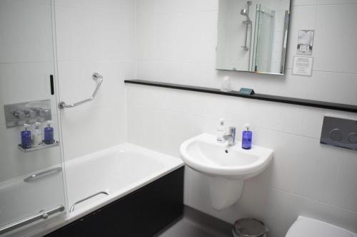 a white bathroom with a sink and a shower at Knoll House in Studland