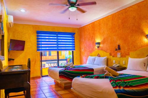 a hotel room with two beds and a ceiling fan at Hacienda Maria Bonita Hotel in Playa del Carmen