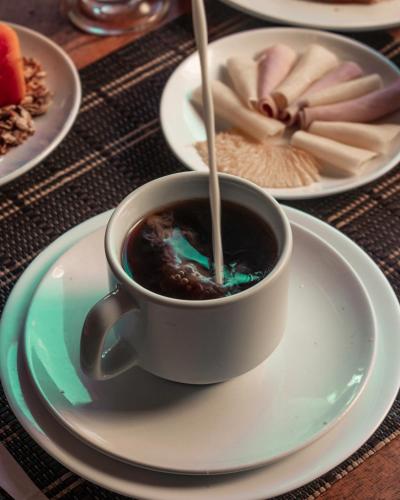a cup of coffee on a plate on a table at Pousada La Cabana in Itacaré