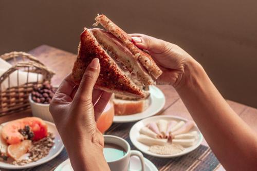 a person holding a sandwich in front of a table at Pousada La Cabana in Itacaré