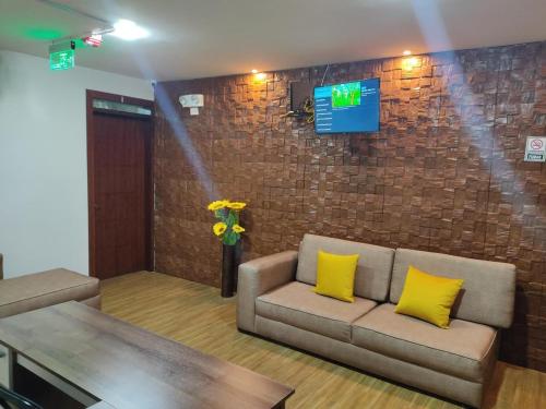 a living room with a couch and a tv on a brick wall at Hospedaje El Girasol TABABELA in Quito