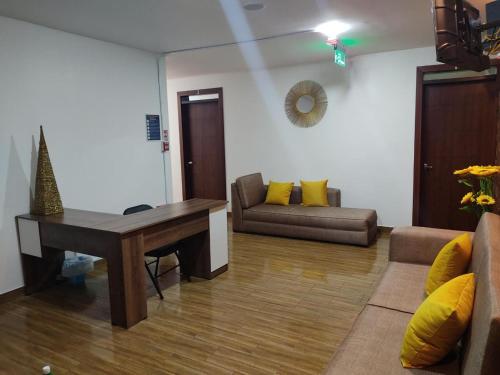 a living room with a desk and a couch at Hospedaje El Girasol TABABELA in Quito