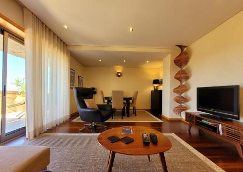 ein Wohnzimmer mit einem TV und einem Tisch in der Unterkunft Casa da Praia in Vila Nova de Gaia