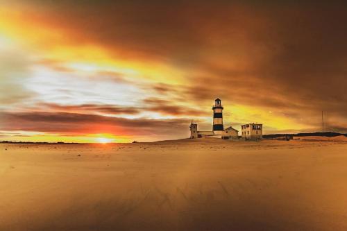 a lighthouse on the beach with a sunset at Lighthouse Villa - Cape Recife in Port Elizabeth