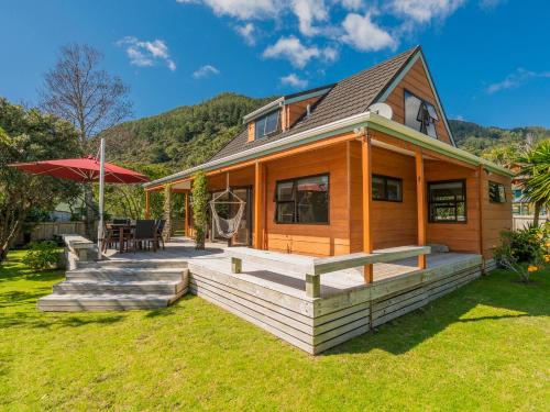a house with a deck with a table and an umbrella at Family Escape - Pauanui Holiday Home in Pauanui