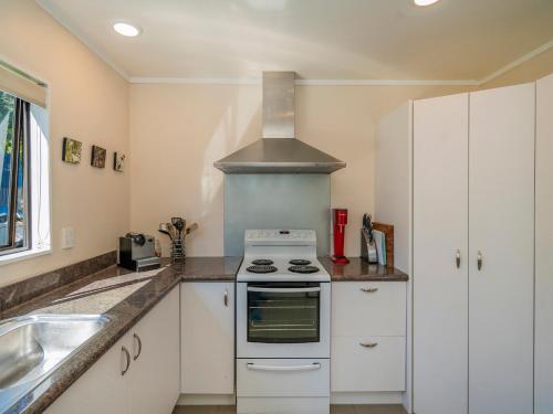 a kitchen with white cabinets and a stove top oven at Family Escape - Pauanui Holiday Home in Pauanui