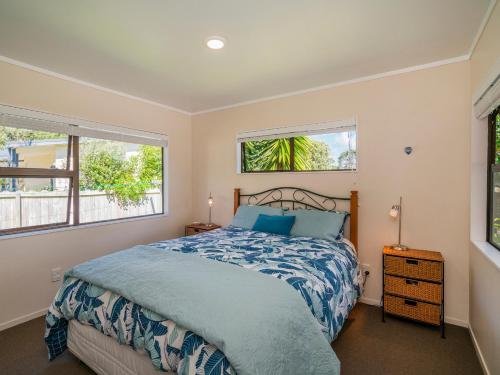 a bedroom with a bed and two windows at Family Escape - Pauanui Holiday Home in Pauanui