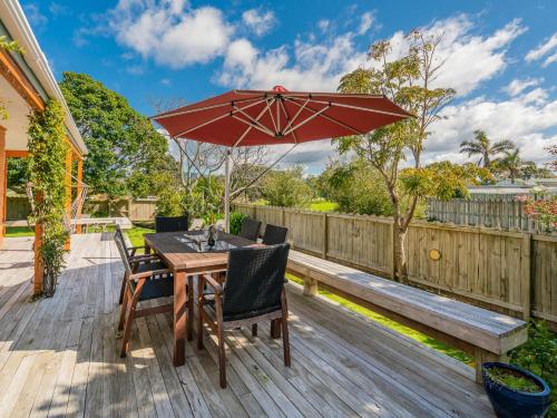 a wooden table and chairs with an umbrella on a deck at Family Escape - Pauanui Holiday Home in Pauanui