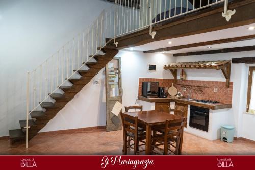 a kitchen with a staircase and a table and chairs at La sosta di Silla in Squille
