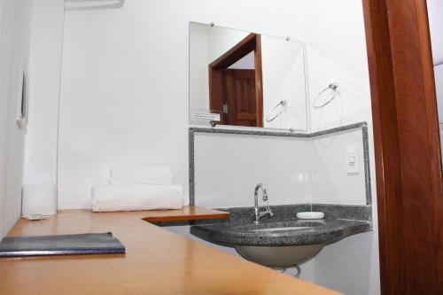 La salle de bains est pourvue d'un lavabo et d'un miroir. dans l'établissement Pousada Vale Du'Carmo, à Pedra Azul