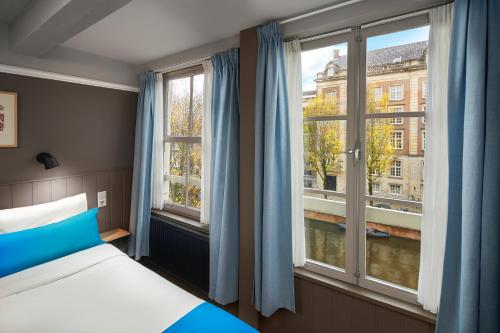 a bedroom with a bed and two windows at Stanley Collection Hotel Hegra Amsterdam in Amsterdam