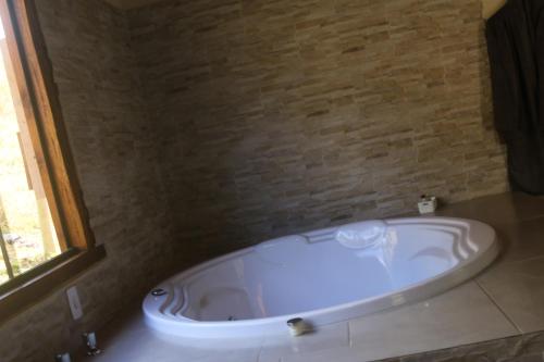 a bath tub in a bathroom with a brick wall at Pousada Leal Chalé in Visconde De Maua