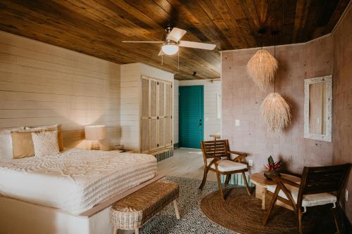 1 dormitorio con 1 cama, mesa y sillas en Tranquilseas Eco Lodge & Dive Center, en Sandy Bay