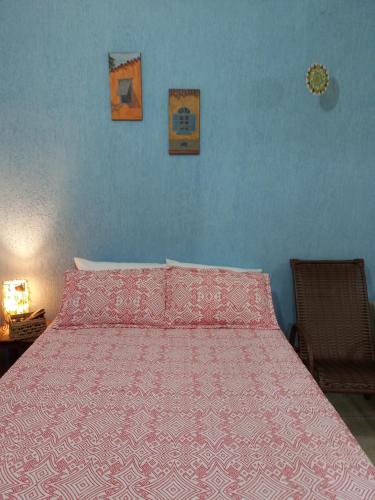 a bedroom with a bed with a pink bedspread at Cantinho do Indaiá - Apto pé na areia in Bertioga