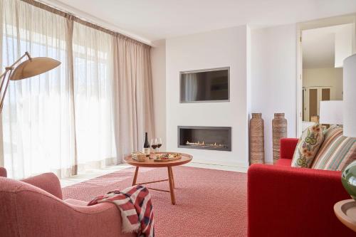 a living room with red furniture and a fireplace at Praia do Canal Nature Retreat - Small Luxury Hotels of the World in Aljezur