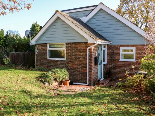 a small brick house with a blue door at Cosy Cottage in Sidley