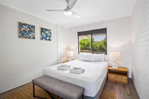 a white bedroom with a large bed and a window at WINDARRA-Alex Headland Family Holiday in Alexandra Headland