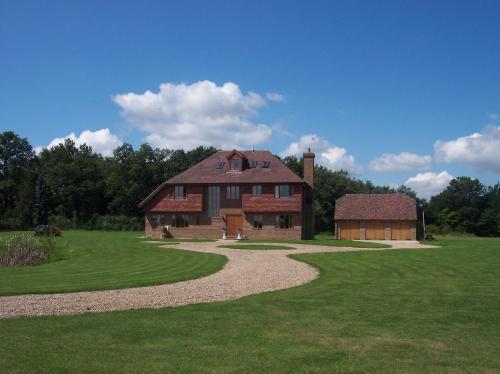a large brick house and a barn in a field at Farmhouse: Beautiful rural location. London from 60 minutes. in Ashford