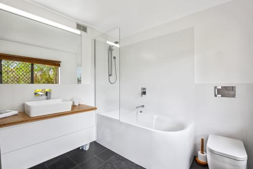 a white bathroom with a tub and a sink at WINDARRA-Alex Headland Family Holiday in Alexandra Headland
