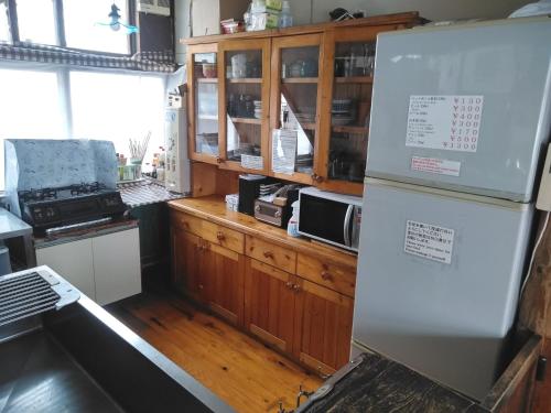 a kitchen with a refrigerator and wooden cabinets at Ekinoyado Hirafu in Kutchan